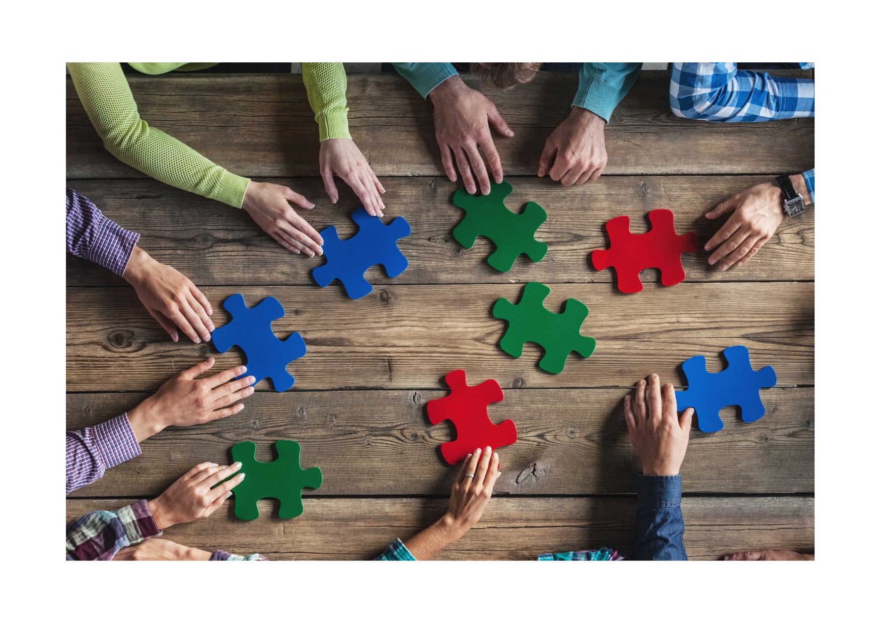 kilkoro ludzi dokłada puzzle do wspólnego obrazka